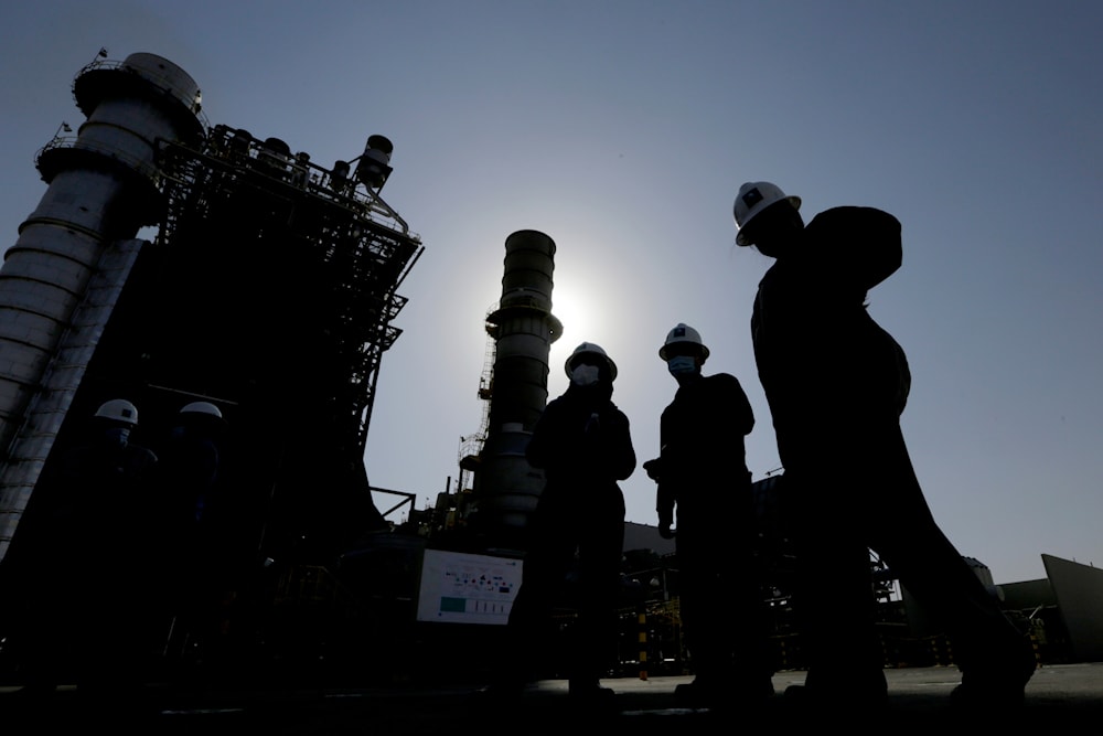 Saudi Aramco engineers walk in front of a gas turbine generator at Khurais oil field during a tour for journalists, outside of Riyadh, Saudi Arabia on June 28, 2021. (AP)