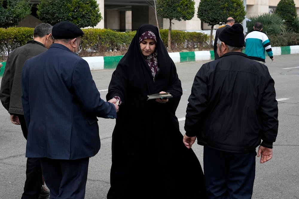 A woman distributes electoral leaflets of a group of candidates for the March 1, election of Assembly of Experts in Tehran, Iran, Friday, Feb. 23, 2024.(AP)