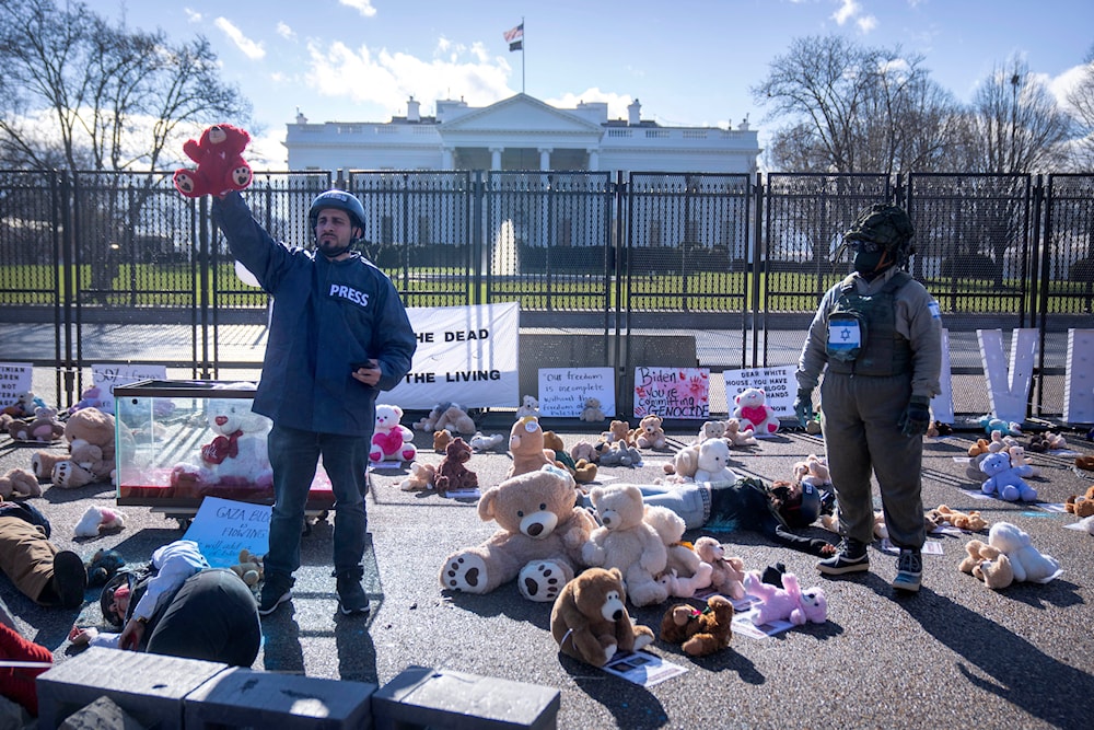 A demonstrator wearing press equipment holds a teddy bear aloft during a commemoration of journalists murdered in Gaza by the IOF, outside of the White House ahead of the March on Washington for Gaza on Saturday, Jan. 13, 2024.(AP)
