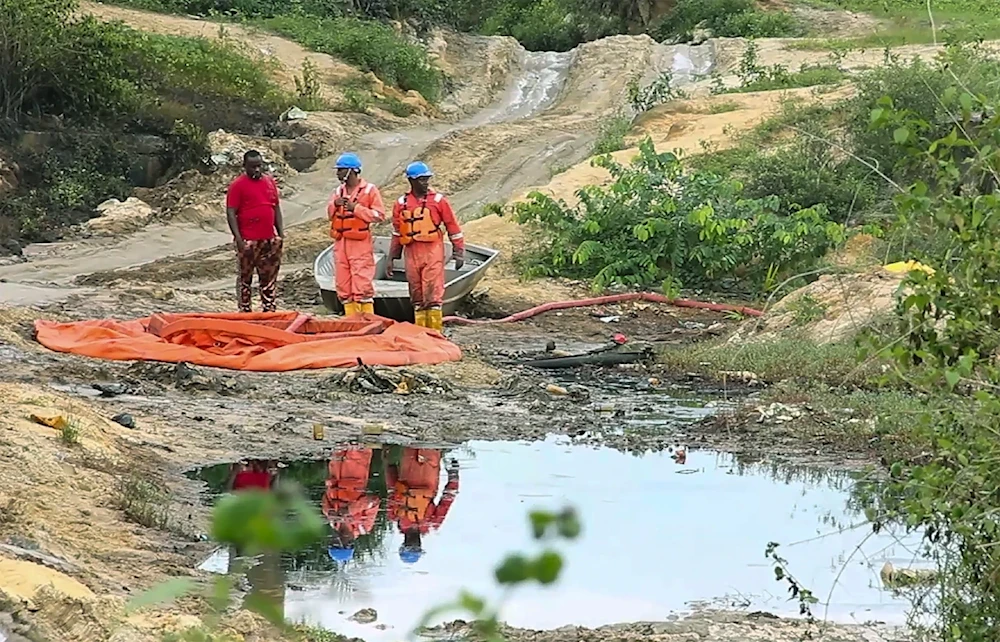 In this grab taken from video, workers stand by a container to collect oil spill waste from an oil spill at a Shell facility in Ogoniland, Nigeria, June 16, 2023. (AP)
