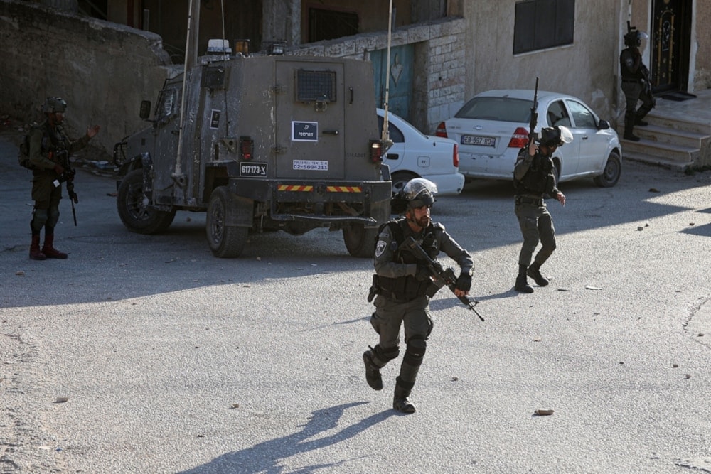 Israeli occupation soldiers advance during a raid on the West Bank town of Beita, August 21, 2023. (AFP)