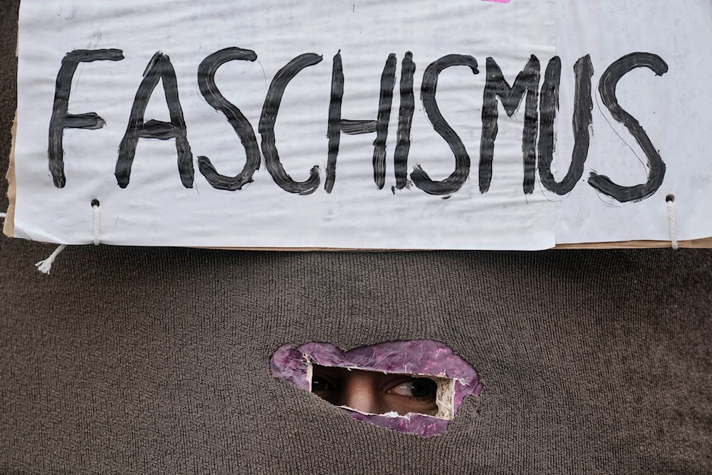 A protestor looks out of a box with the writing 'Fascism' at a demonstration against the AfD party and right-wing extremism in Berlin, Germany, Saturday, Feb. 3, 202(AP)