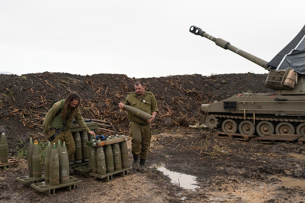 Israeli soldiers prepare to load a mobile howitzer in the north of occupied Palestine, near the occupied Lebanese-Palestinian border area, January 15, 2024 (AP)