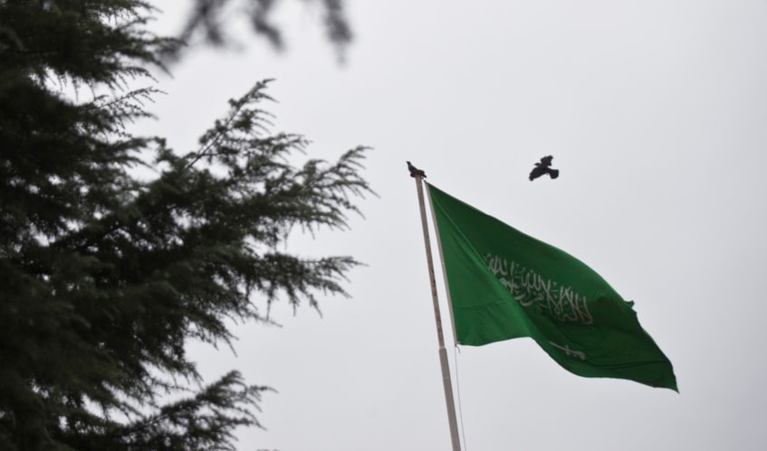 A bird flies next to Saudi Arabia's flag at the roof top of their consulate buidling in Istanbul, Sunday, Oct. 14, 2018.