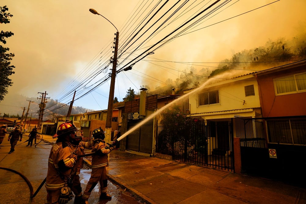 Firefighters protectively spray water on homes as forest fires burn nearby, in Vina del Mar, Chile, Saturday, Feb. 3, 2024. (AP)