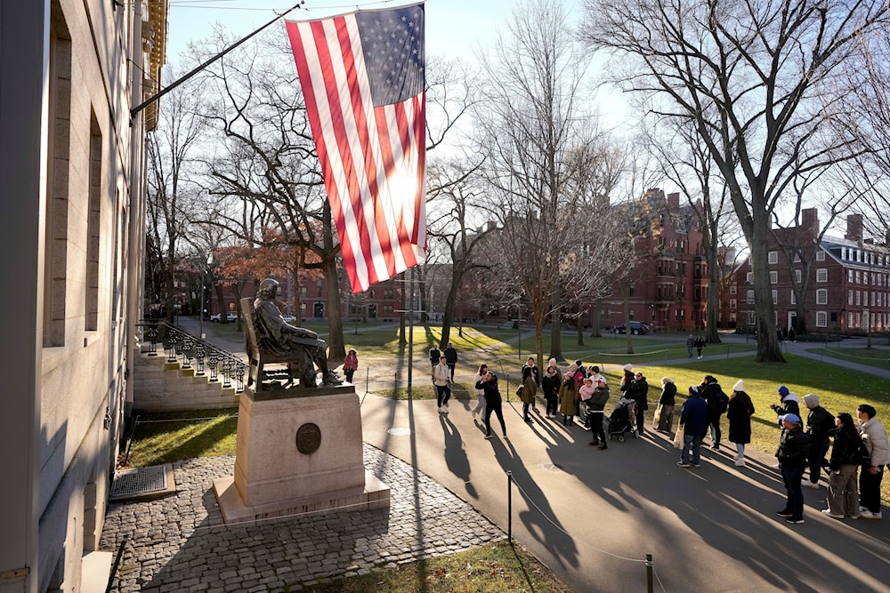 People take photographs near a John Harvard statue, left, Tuesday, Jan. 2, 2024, on the campus of Harvard University, in Cambridge, Massachusetts (AP)