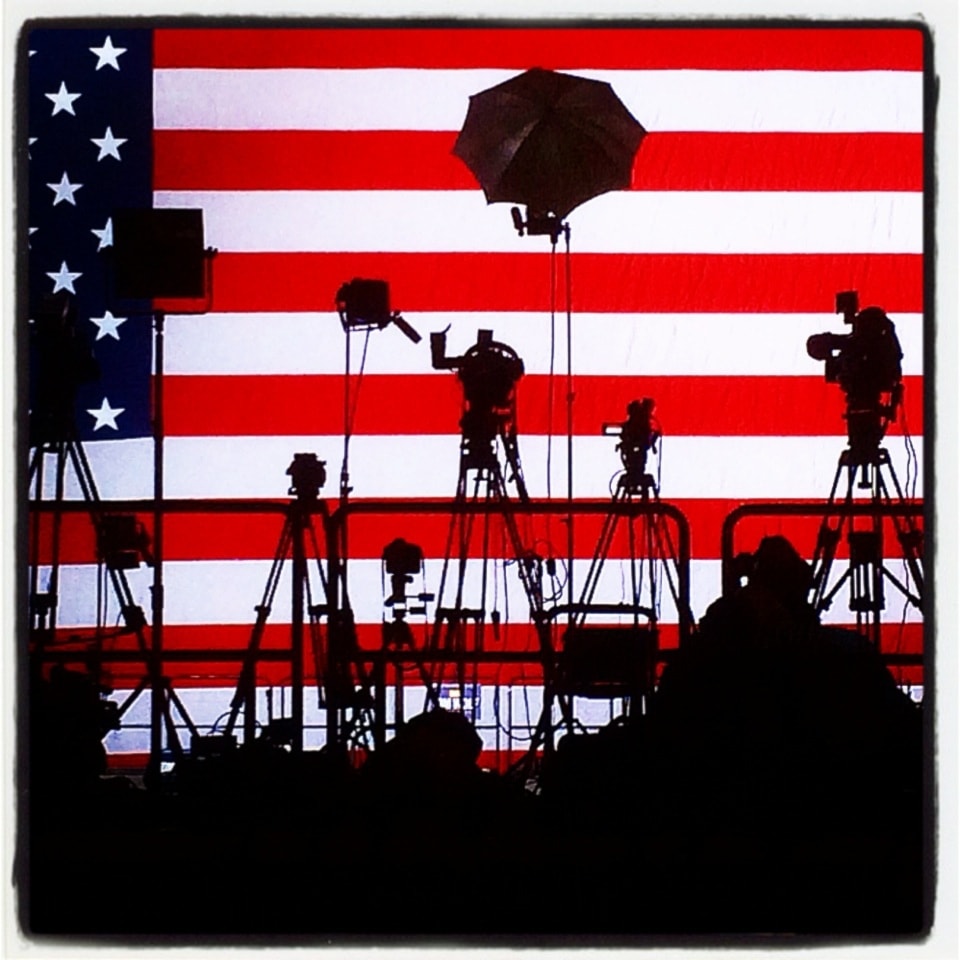 Cameras set up on tripods are silhouetted against an American flag backdrop on the stage where Pennsylvania Democratic Governor-elect Tom Wolf spoke in York, Pa. on Tuesday, Nov. 4, 2014(AP)