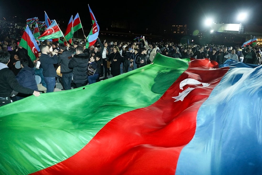 People carry a huge national flag celebrating Azerbaijan's President Ilhan Aliyev's victory in the presidential election in Baku, Azerbaijan, Wednesday, Feb. 7, 2024. (AP)