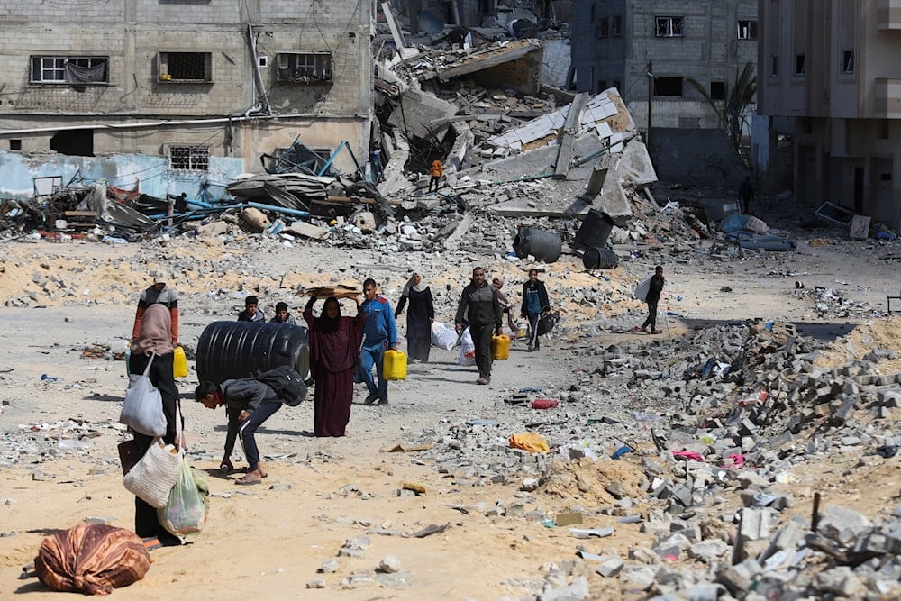 Palestinians walk through the destruction left by