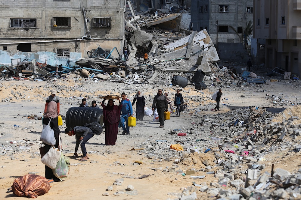 Palestinians walk through the destruction left by 