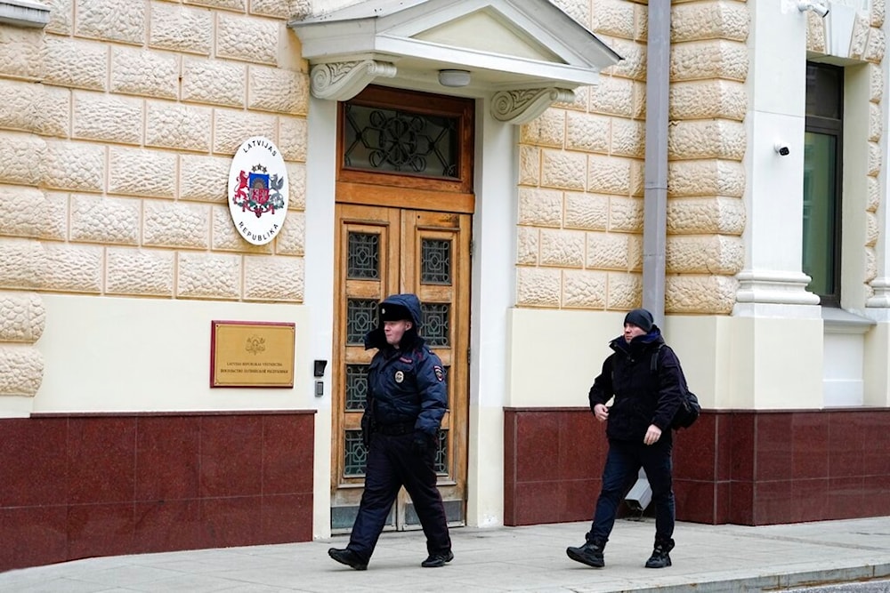 A Russian police officer and a man walk at the Latvian Embassy's building in Moscow, Russia, Tuesday, Jan. 24, 2023. (AP)