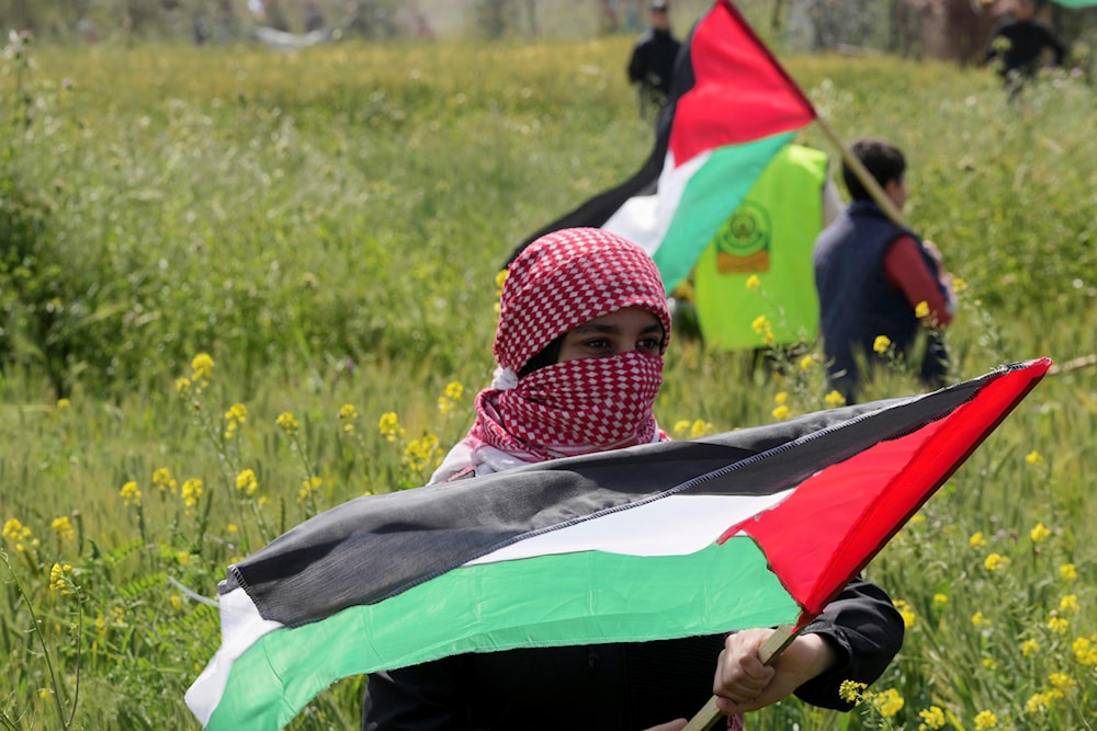 Palestinians wave flags during a rally marking the 47th anniversary of Land Day, east of Gaza City, occupied Palestine, March 30, 2023 (AP)