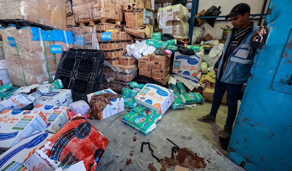 UNRWA UN (United Nations) staff stands near a pool of blood at an UNRWA warehouse and distribution centre in Rafah, in the southern Gaza Strip, following an Israeli strike on March 13, 2024 (AFP)