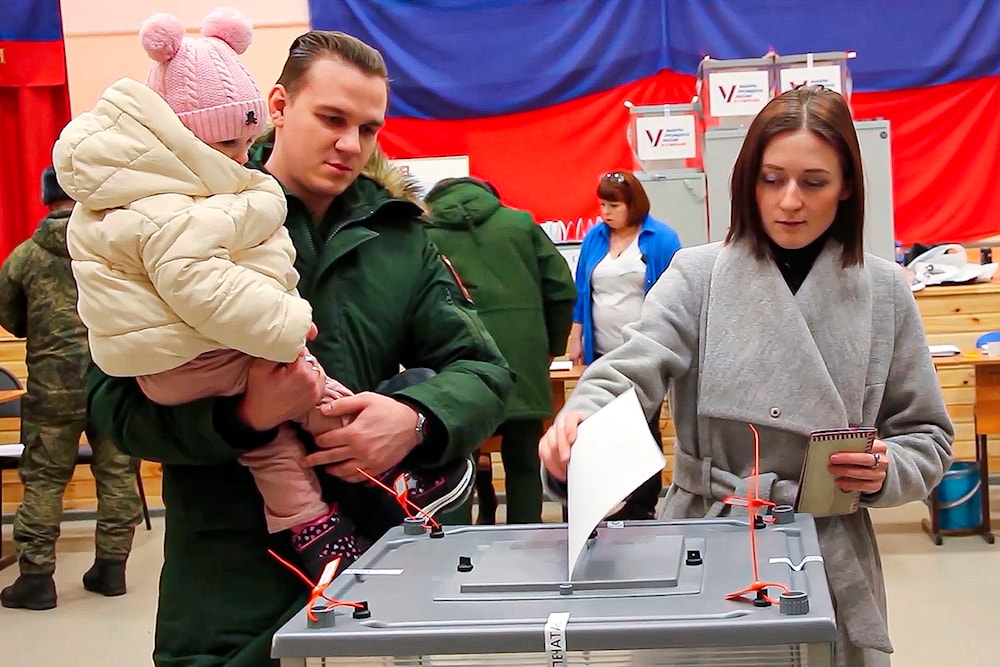 Photo by the Russian Defense Ministry Press Service on March 15, 2024, a Russian serviceman is with his child as his wife casts her ballot at a polling station during the presidential election at an undisclosed location in Russia. (AP)