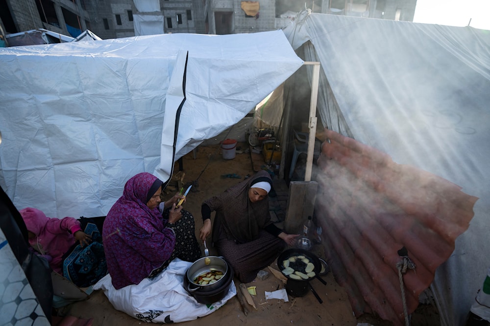 Randa Baker, Right, who was displaced by the Israeli bombardment of the Gaza Strip, prepares the Iftar meal with her mother on the first day of Ramadan at a makeshift tent camp in the al-Mawasi area, southern Gaza, March 11, 2024. (AP)