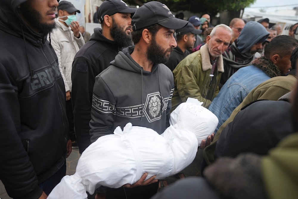 A Palestinian carries a relative killed in the Israeli bombardments of the Gaza Strip in front of the morgue of the Al Aqsa Hospital in Deir al Balah, Gaza Strip, on Thursday, March 7, 2024. (AP)