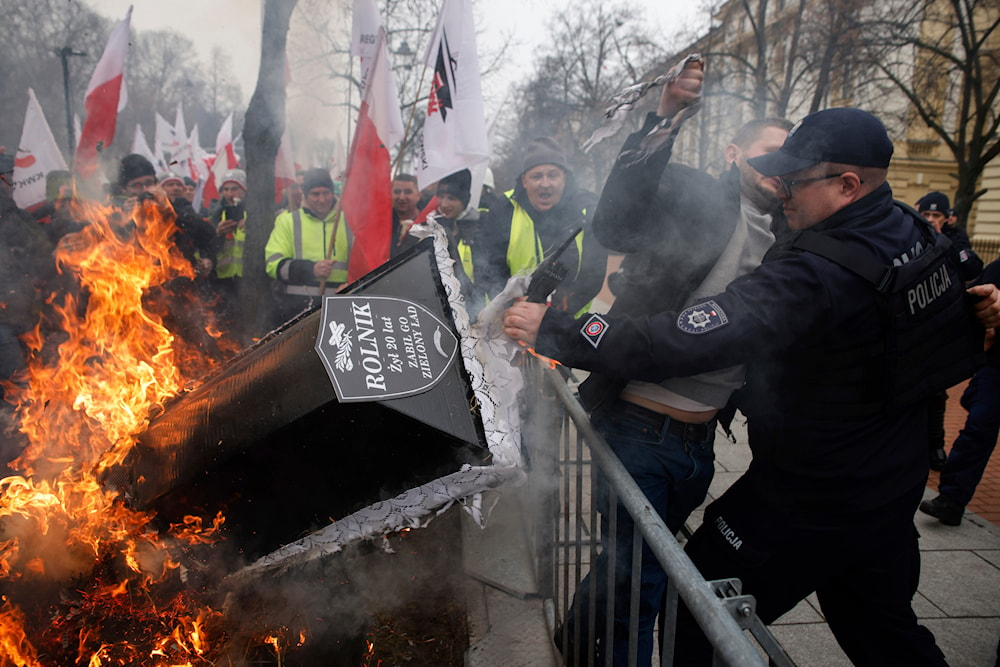 A police officer stops a protester by a burning coffin during a protest in Warsaw, Poland, on Wednesday, March 6, 2024. (AP)