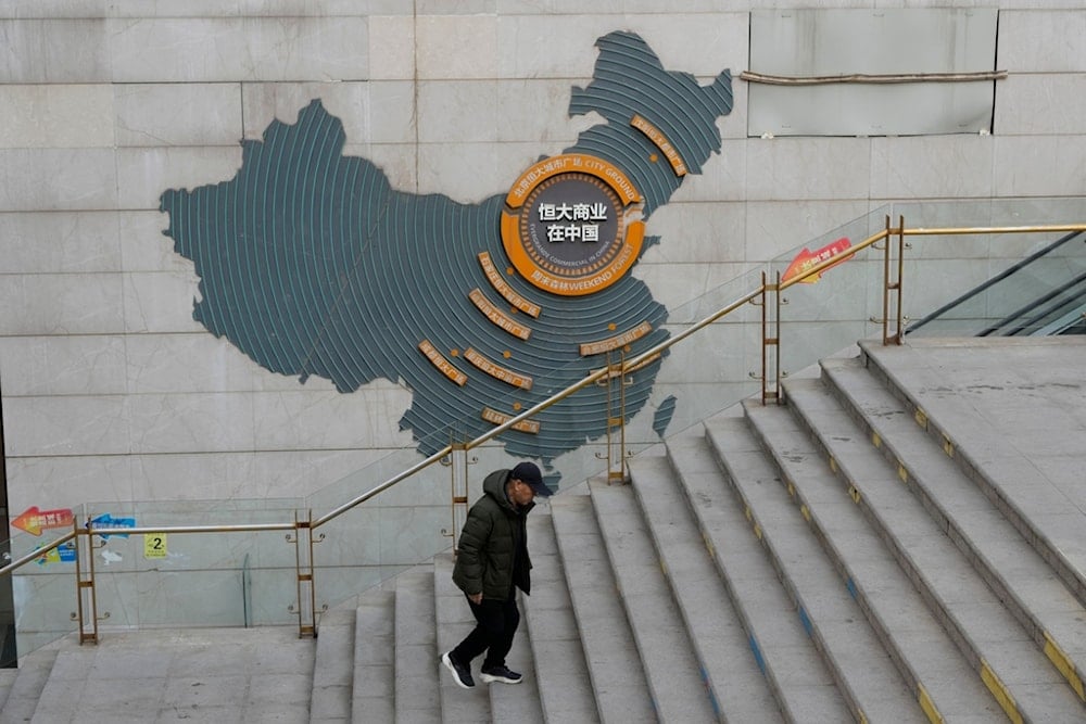 A man walks past a depiction of Evergrande properties across a China map at a partially shuttered Evergrande commercial complex in Beijing, Monday, Jan. 29, 2024. (AP)