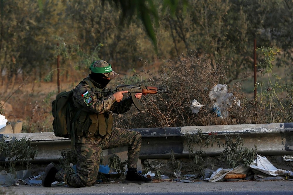 A freedom fighter from Al-Qassam Brigades, the military wing of Hamas, takes a position to secure his colleagues marching along the main road of Nusseirat Refugee camp, central Gaza Strip, Thursday, Oct. 28, 2021. (AP)