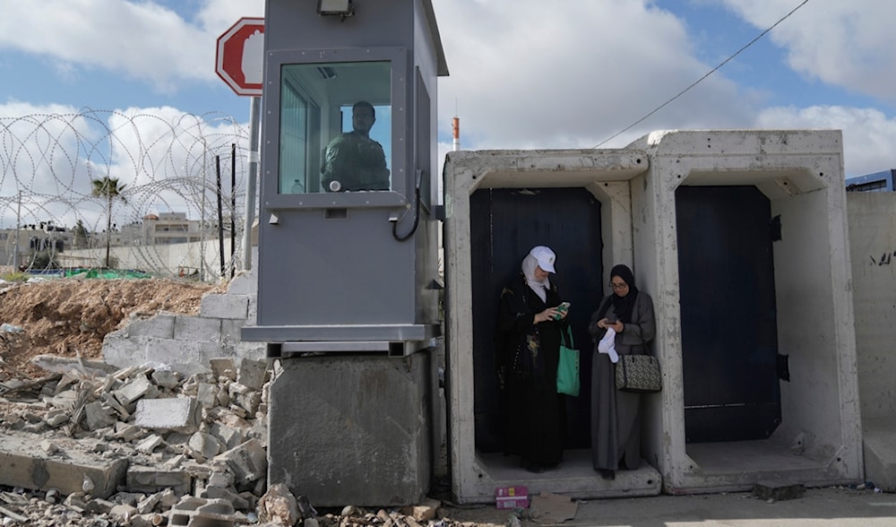 Palestinian women wait to cross the Israeli occupation's Qalandia checkpoint near the occupied West Bank city of Ramallah to al-Quds in occupied Palestine, March 15, 2024. (AP)