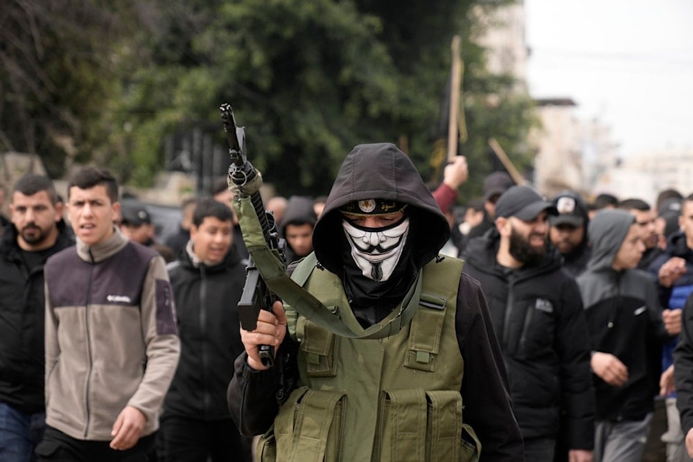 A masked gunman marches alongside of the bodies of Said Jaradat and Yasser Hanoun, both draped in the flag of the Palestinian Islamic Jihad Resistance movement, on Friday, Feb. 23, 2024. (AP)