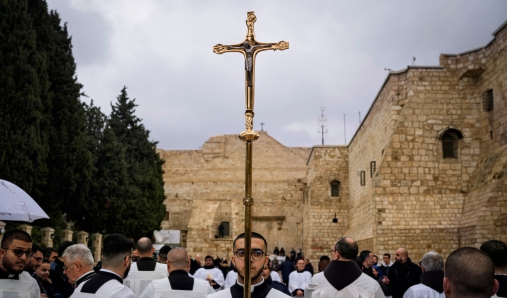 Catholic clergy walk in procession next to the Church of the Nativity, on Christmas Eve, in the West Bank city of Beit Lahm, occupied Palestine, Dec. 24, 2023. (AP)