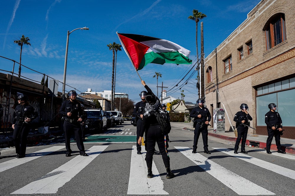 A protester waves a Palestinian flag in front of law enforcement officers as hundreds demonstrate in support of Palestinians near the Dolby Theatre where the 96th Academy Awards Oscars ceremony is held on Sunday, March 10, 2024, in Los Angeles. (AP)