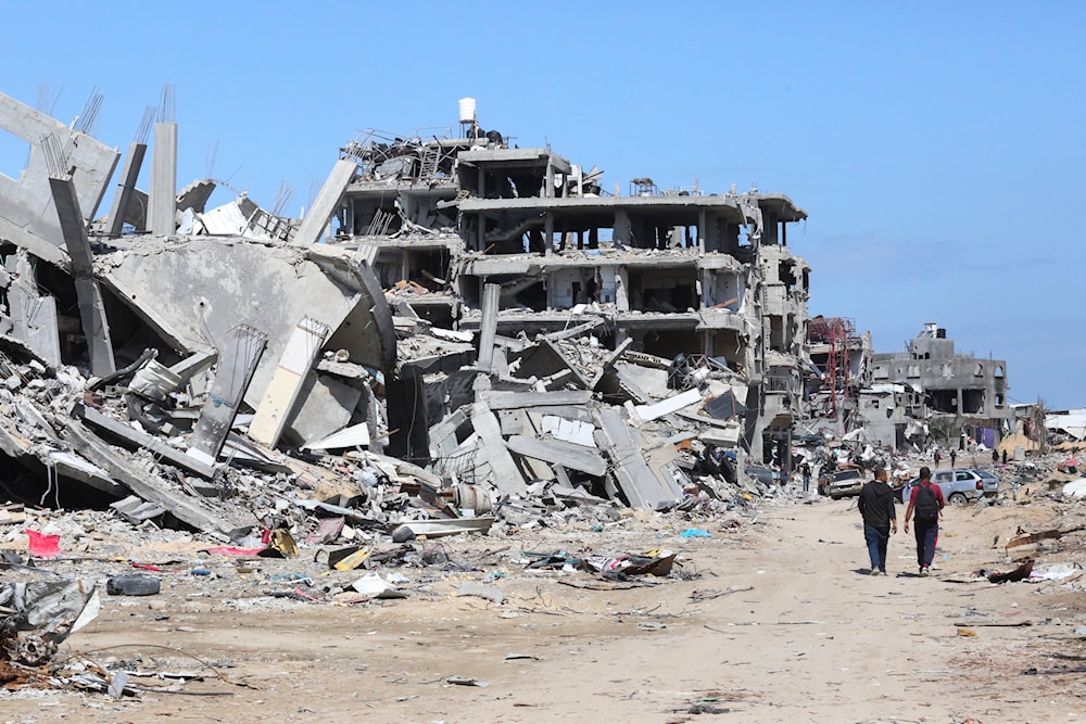 Palestinians walk through the destruction left by the Israeli aggression on Khan Younis, Gaza Strip, occupied Palestine, March 8, 2024 (AP)