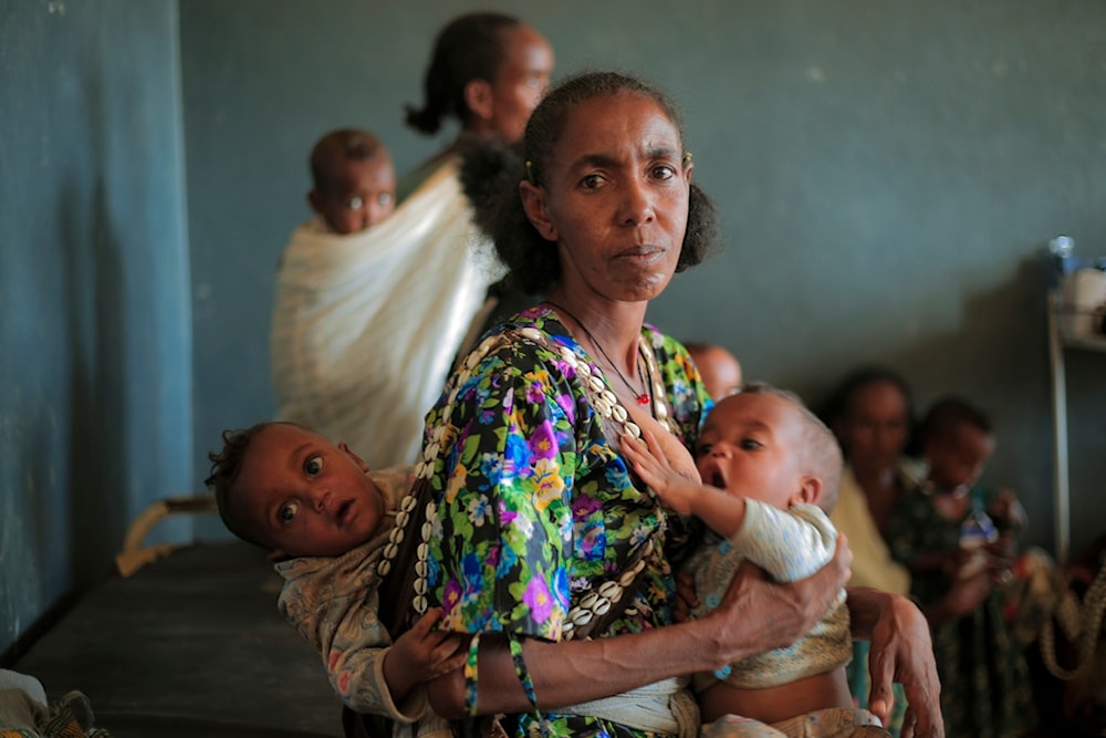 Ada Arae Girmay, 40, holds her babies Assefa and Metkel at the Finarwa Health Center in Nebar Hadnet, in the Tigray region of northern Ethiopia, on Tuesday, Feb. 27, 2024. (AP Photo/Amir Aman Kiyaro)