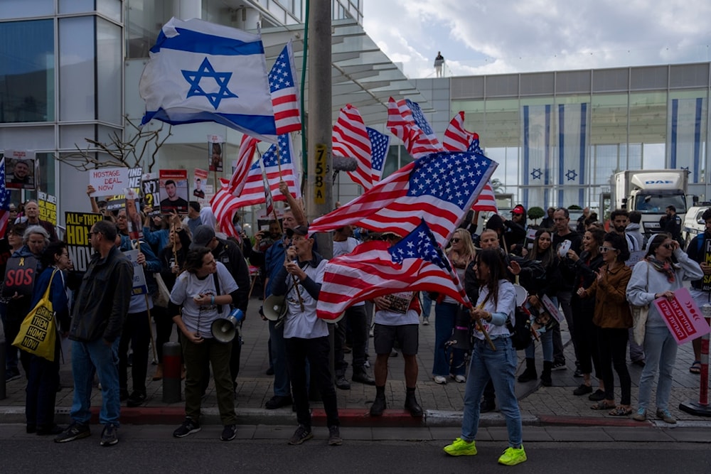 Protestors wave Israeli and US flags during outside a meeting held between US Secretary of State Antony Blinken and families of captives, in 'Tel Aviv', occupied Palestine, March 22, 2024. (AP)
