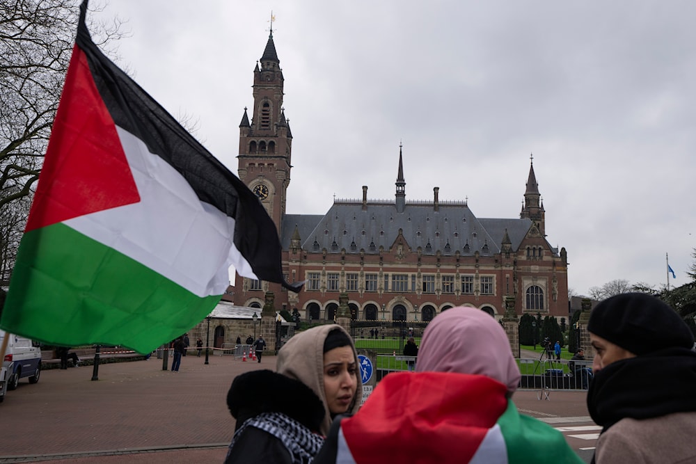A Palestinian flag flies outside the United Nations' highest court, rear, during historic hearings in The Hague into the Israeli occupation of occupied Palestine, Netherlands, Wednesday, February 21, 2024 (AP)