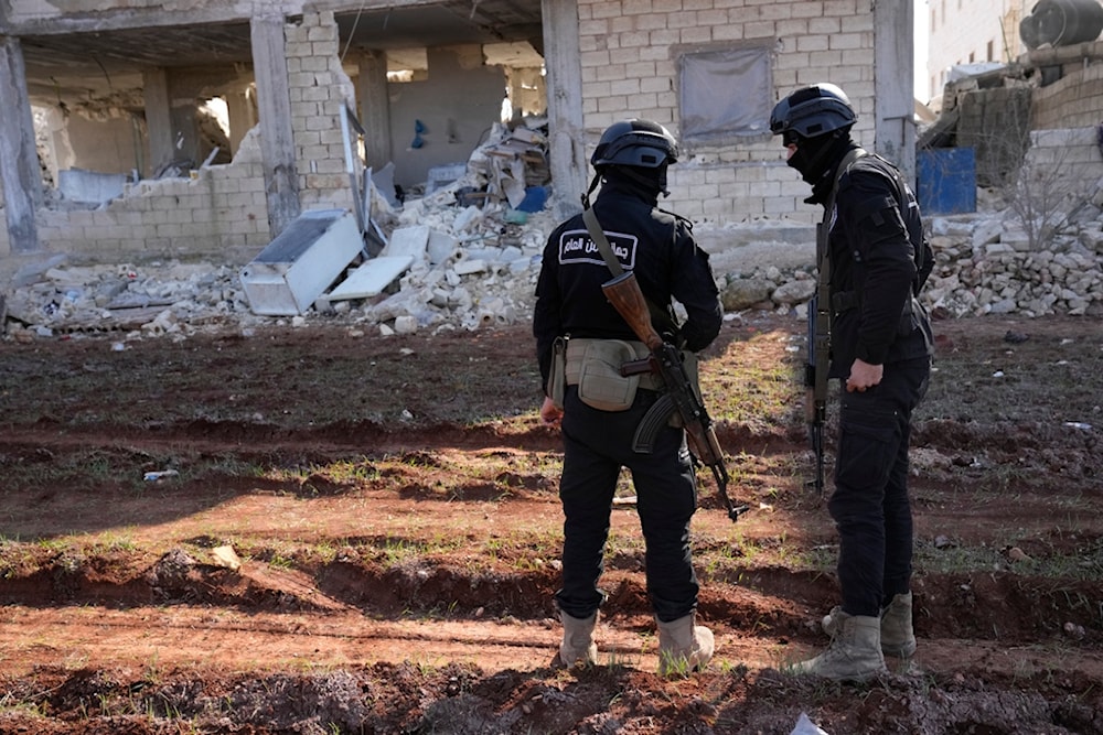 Militants of the terrorist organization Hayat Tahrir al-Sham stand in front of a destroyed house in Atareb, Syria, Sunday, Feb. 12, 2023. (AP)