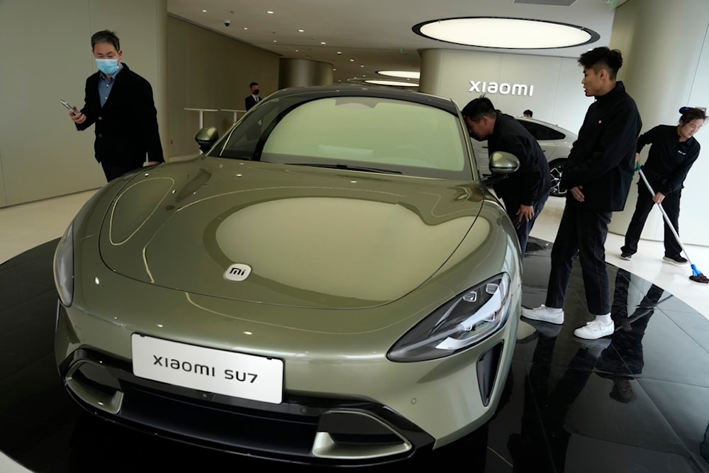 Visitors to the Xiaomi Automobile flagship store looks at the Xiaomi SU7 electric car on display in Beijing, Tuesday, March 26, 2024 (AP)