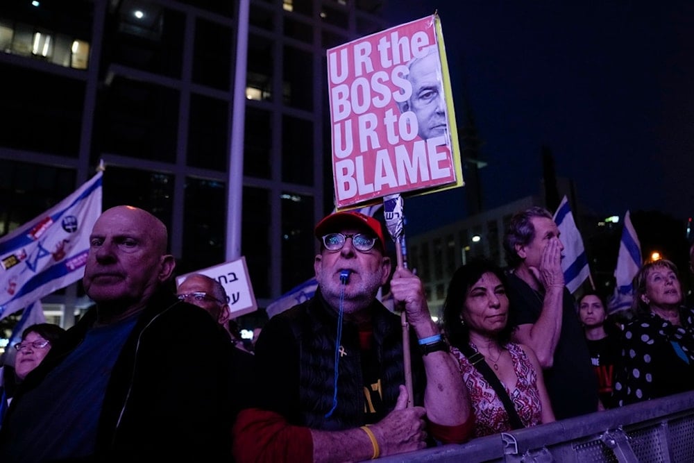 A man holds up a sign with an image depicting Israeli Prime Minister Benjamin Netanyahu's during a protest on March 30, 2024, in 