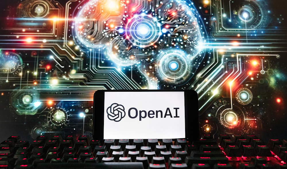 The OpenAI logo is displayed on a cell phone with an image on a computer screen generated by ChatGPT's Dall-E text-to-image model, Dec. 8, 2023 (AP)