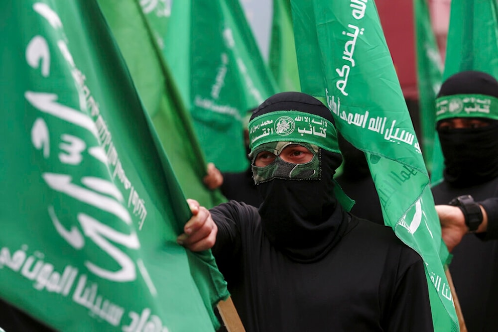 Masked Hamas fighter wave their green flags during a protest, February 14, 2020 (AP)