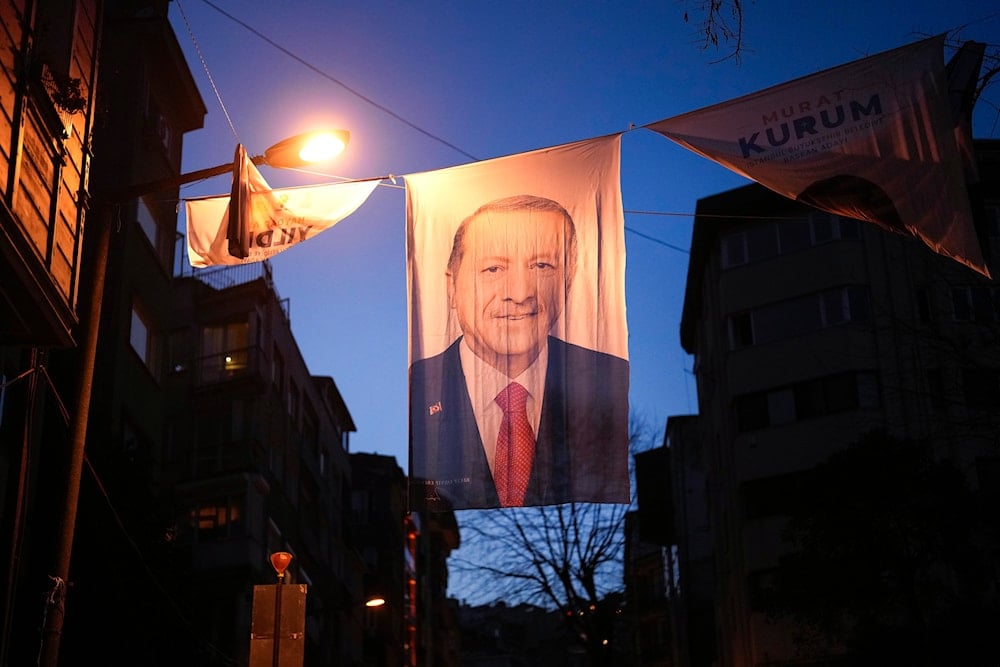 People walk under a campaign banner of Turkish President and leader of the Justice and Development Party, or AKP, Recep Tayyip Erdogan, in Istanbul, Turkey, Friday March 29, 2024. (AP)