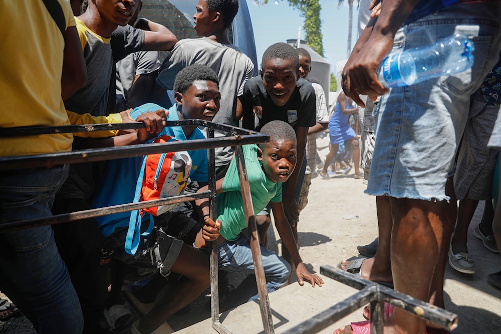 Youth take cover after hearing gunshots at a public school that serves as a shelter for people displaced by gang violence, in Port-au-Prince, Haiti on March 22, 2024. (AP)