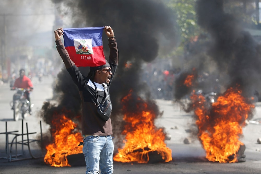 A demonstrator holds up an Haitian flag during protests demanding the resignation of Prime Minister Ariel Henry in Port-au-Prince, Haiti, Friday, March 1, 2024. (AP)