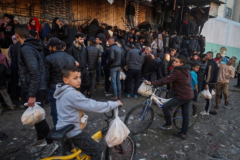 Palestinian crowds struggle to buy bread from a bakery in Rafah, Gaza Strip, February 19, 2024 (AP)