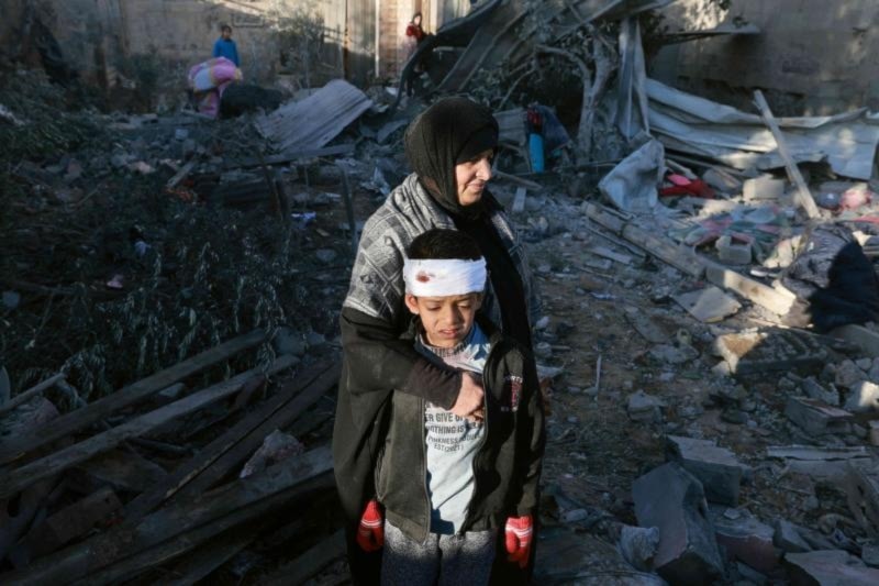 A Palestinian mother embraces a lightly-injured boy as they check the rubble of a residential building following Israeli bombardment, January 18, 2024 in Rafah in the southern Gaza Strip. (AFP)