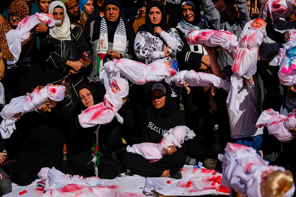Women cradle mock bodies of dead Palestinian children wrapped in blood-stained blankets, during a sit-in in Beirut, Lebanon, Friday, Nov. 17, 2023. (AP)