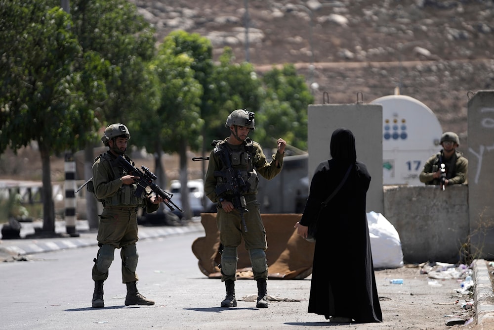 Israeli forces stand in the way of a Palestinian woman in an illegal settlement on Aug. 30, 2023. (AP)