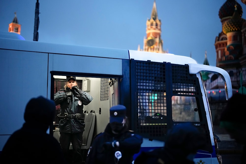 A police officer stands in a police bus with detained demonstrators during an anti-war protest near Red Square with St. Basil's Cathedral in Moscow, Russia, on Sept. 24, 2022. (AP)