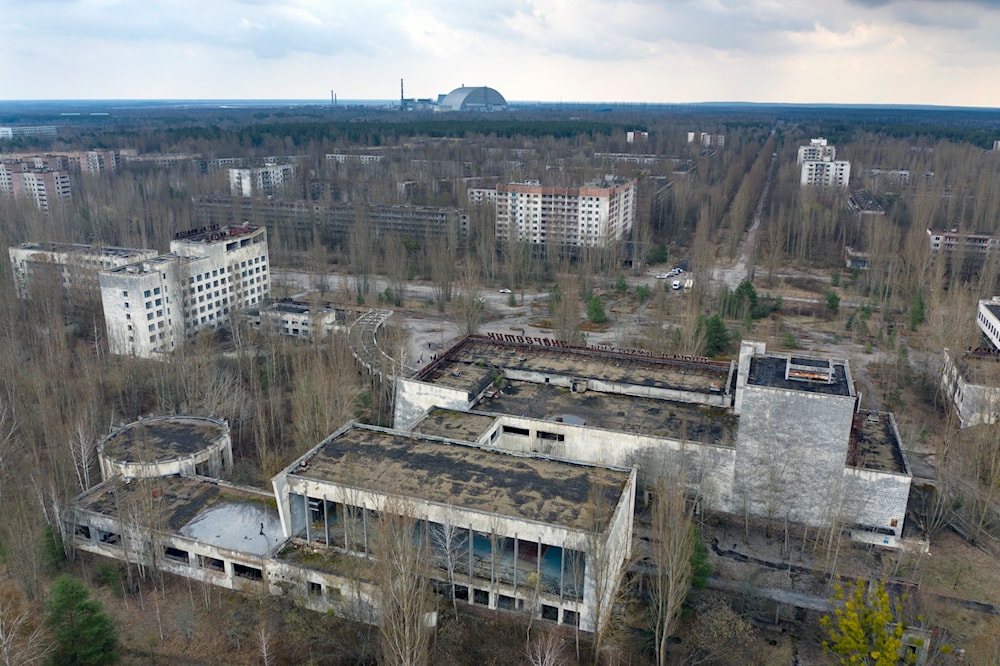 A view of the ghost town of Pripyat with a shelter covering the exploded reactor at the Chernobyl nuclear plant in the background, Ukraine, April 15, 2021 (AP)