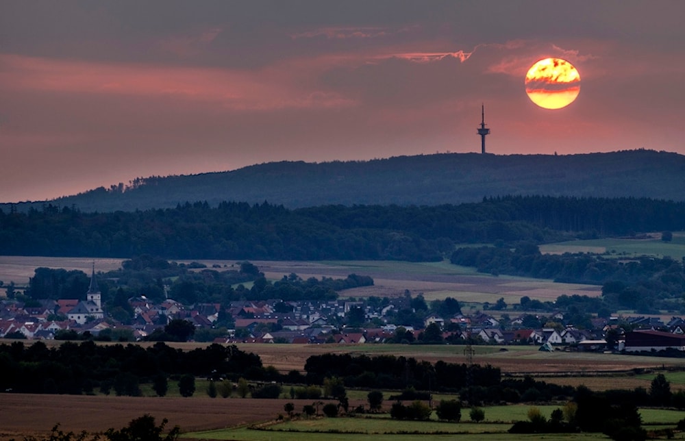 The sun rises over the village of Wehrheim near Frankfurt, Germany, Thursday, Aug. 10, 2023. (AP Photo/Michael Probst)