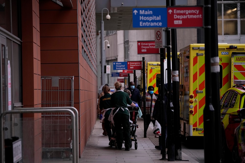 A patient is pushed on a trolley after arriving in an ambulance outside the Royal London Hospital in the Whitechapel area of east London, on January 6, 2022. (AP)