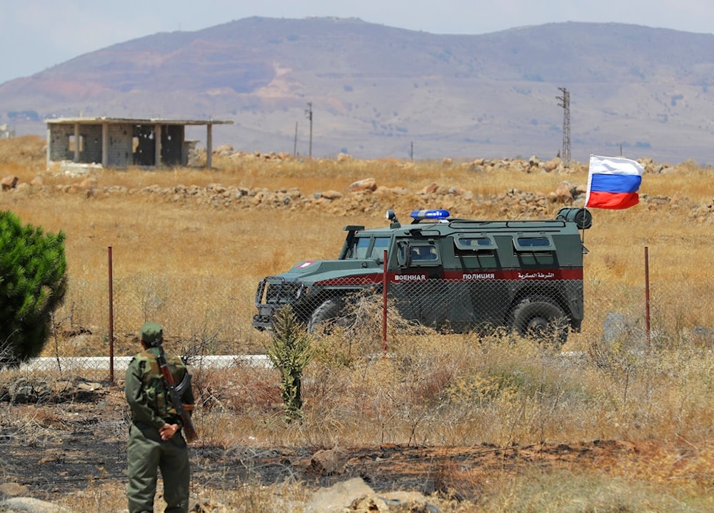Syrian army soldier stands guard as Russian military police vehicle passes by near the town of Alhureyeh, Syria, Tuesday, Aug. 14, 2018. (AP)
