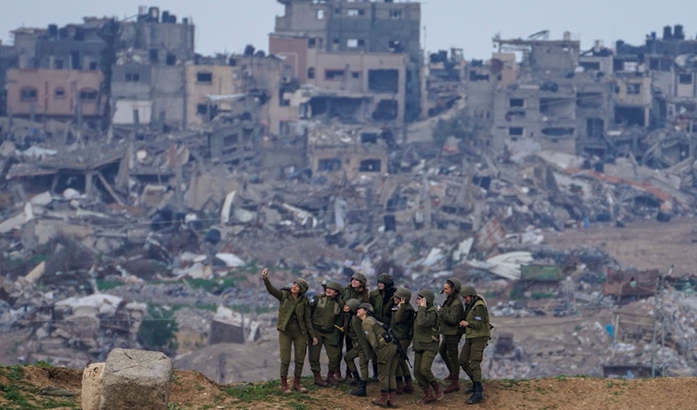 Israeli female soldiers pose for a photo in front destroyed buildings in Gaza, Feb. 19, 2024. (AP)