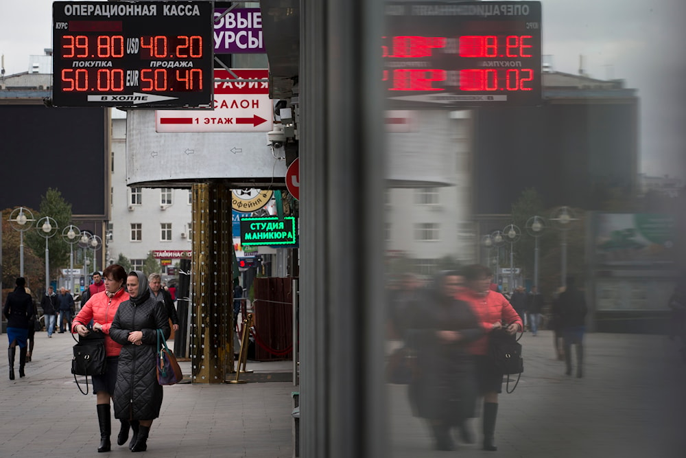 People walk past money exchange offices in Moscow, Russia, Monday, Oct. 6, 2014. (AP)